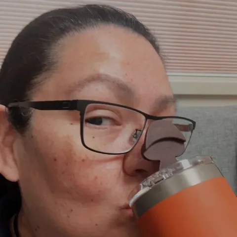 Customer in glasses sipping RYZE from her orange tumbler