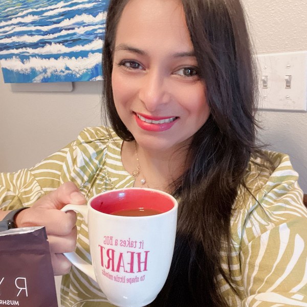 JOAN J. M. holding her coffee beside a RYZE Mushroom Coffee pouch