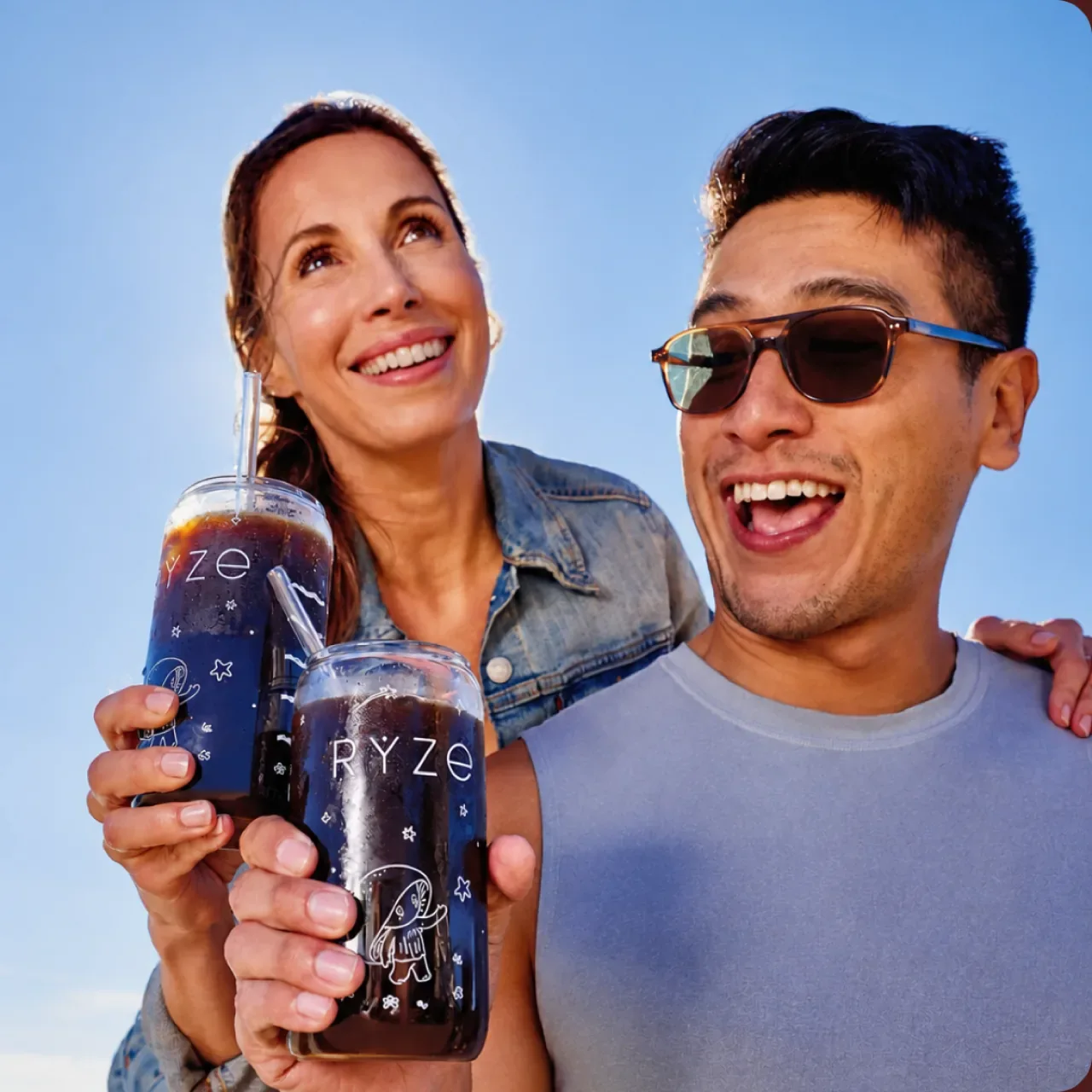 A couple outdoors laughing together, each holding a RYZE cold brew