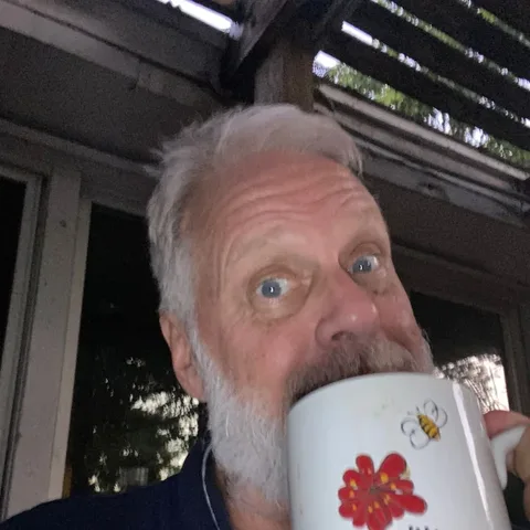 Customer with a white beard sipping his morning RYZE from a flower mug