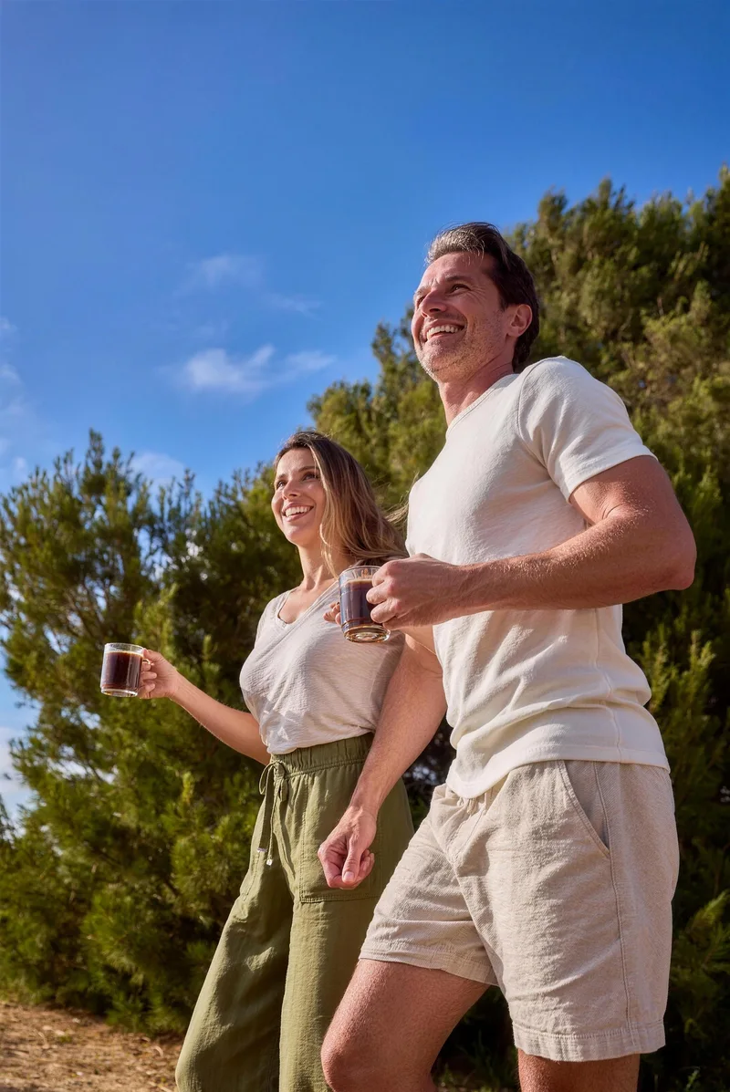 Couple walking outdoors with RYZE mugs in the morning sun