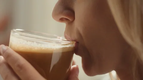 Close-up of someone sipping a creamy RYZE mushroom coffee