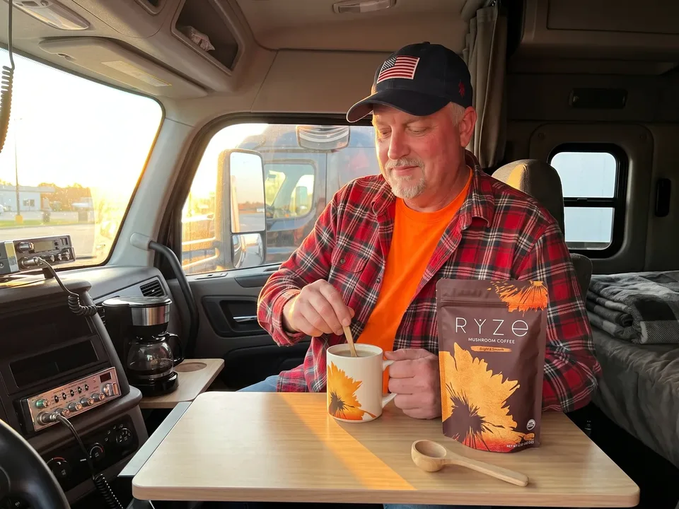 The truck driver from the ad making his morning cup in the parked sleeper cab with the approved cream RYZE mug, wooden scoop, and brown Bright & Smooth pouch.