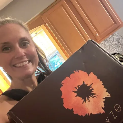 Customer smiling in her kitchen holding her RYZE box