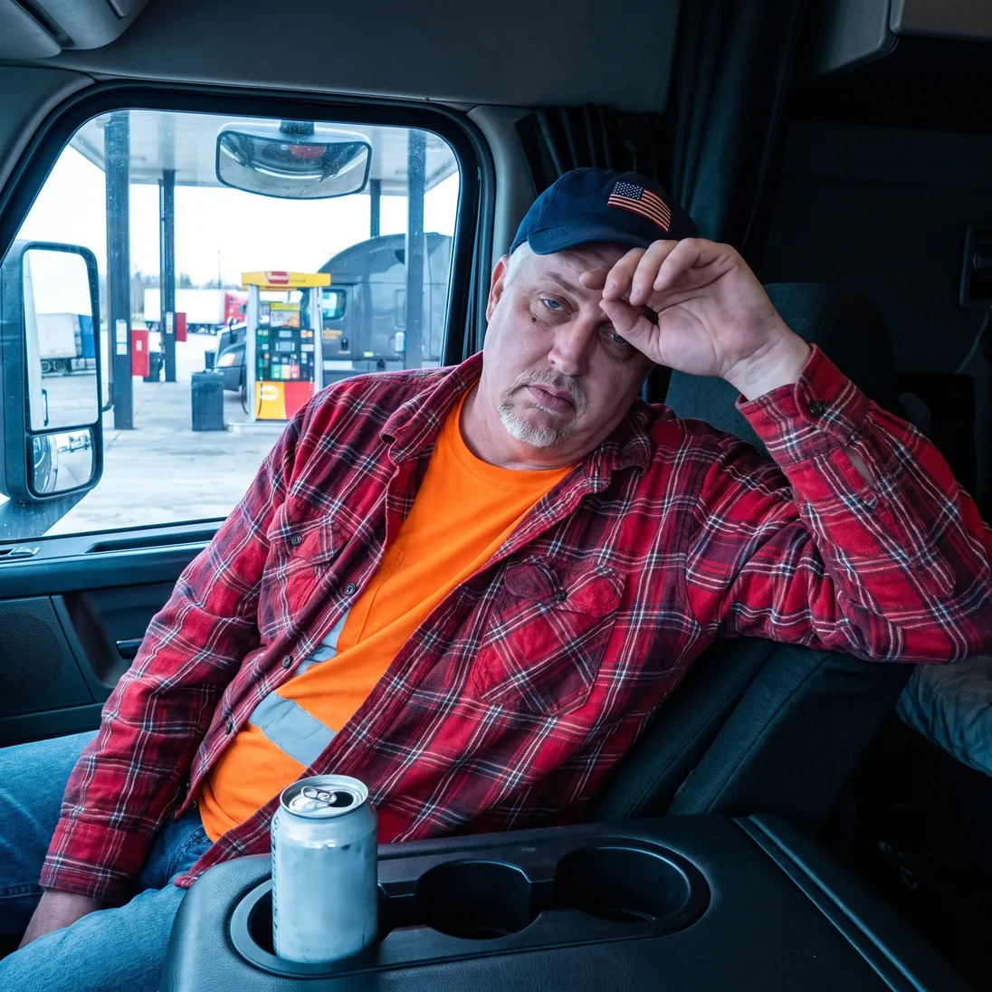 The truck driver from the ad slumped in his cab beside an energy-drink can during a long afternoon drive.