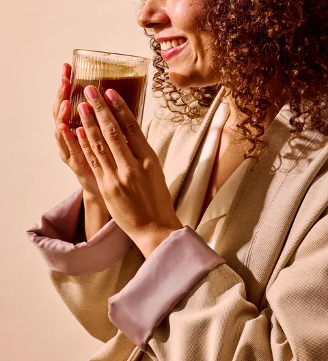 Hands cradling a warm glass of RYZE mushroom coffee