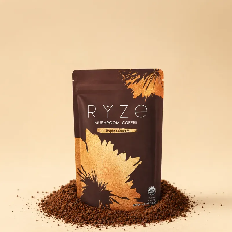 RYZE Mushroom Coffee bag standing in fresh coffee grounds