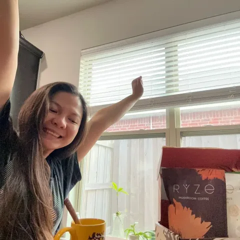 Customer cheering at her kitchen table with her mug and RYZE starter box
