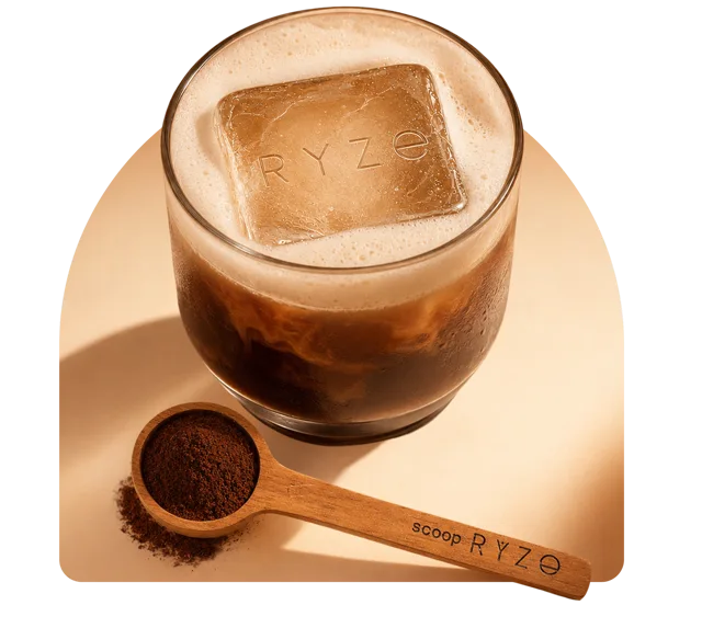 Iced RYZE mushroom coffee latte in a glass with a branded ice cube and a wooden scoop