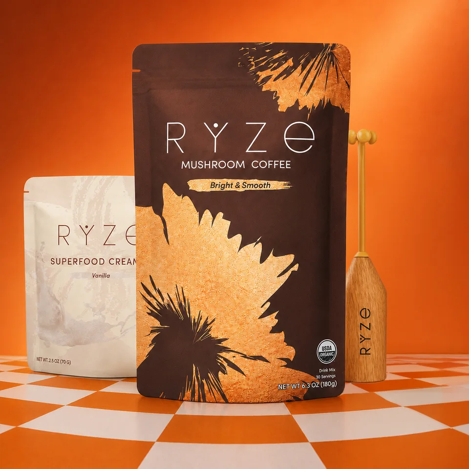 RYZE Mushroom Coffee and Superfood Creamer pouches with a wooden frother